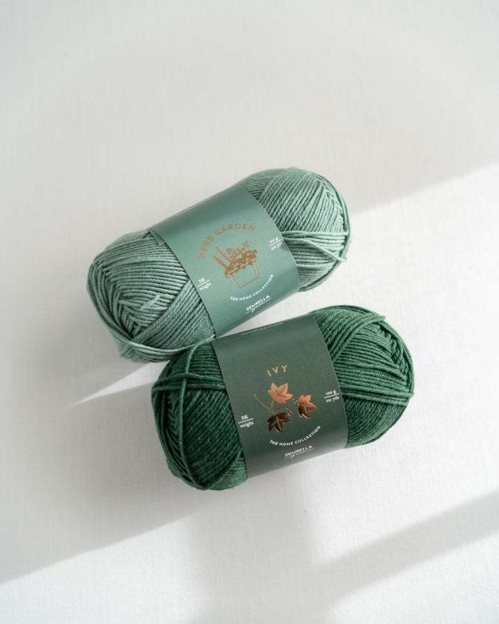 Two skeins of green yarn with labels on a white background