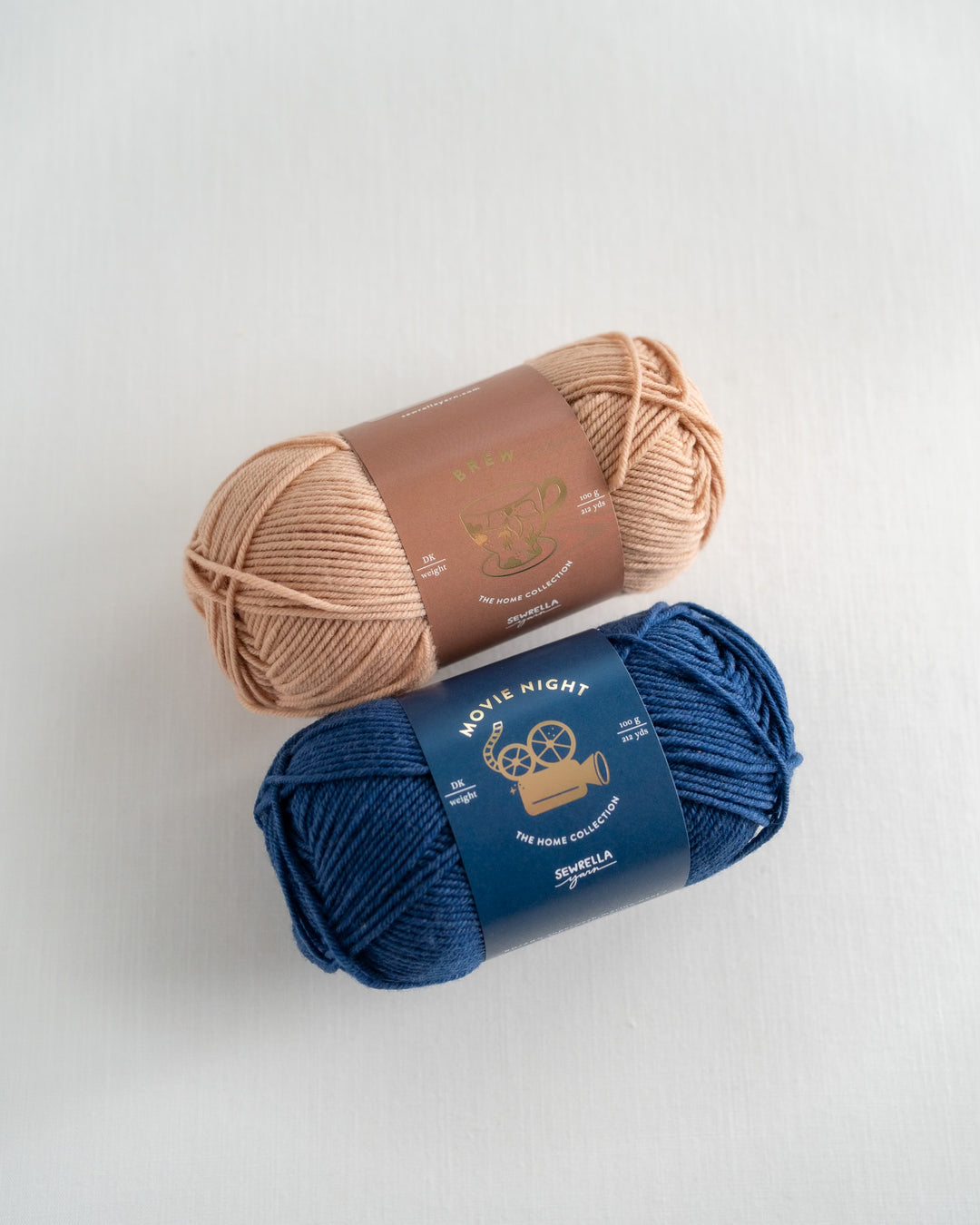 Two skeins of yarn, one beige and one blue, on a light gray background.